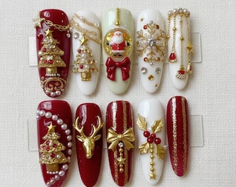 May include: A set of ten artificial nails with festive Christmas designs. The nails feature a variety of decorations, including miniature Christmas trees, snowflakes, Santa Claus, bows, and gold accents. The color palette includes red, white, and gold.