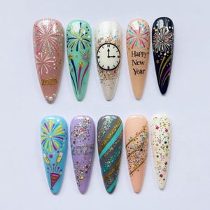 May include: A collection of ten artificial nails with festive New Year's designs. Each nail features unique artwork, including fireworks, clocks, and the text "Happy New Year" and "2025". Colors include pink, blue, green, and gold.