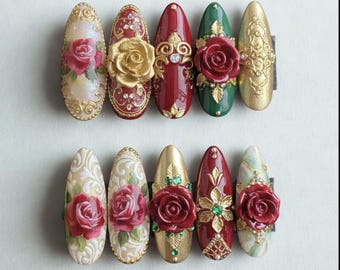 May include: A collection of ten ornate, almond-shaped artificial nails. The nails feature a variety of designs, including gold filigree, red roses, and jewel accents. Colors include gold, red, green, and cream.