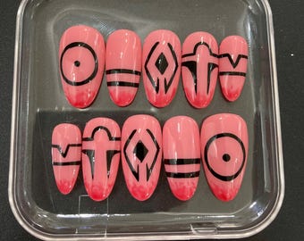 Może przedstawiać: Zestaw dziesięciu sztucznych paznokci w przezroczystym plastikowym etui. Owalne paznokcie mają różową bazę i czarne geometryczne wzory. Wzory obejmują okręgi, linie i romby. Końcówki paznokci mają ciemniejszy różowy gradient.