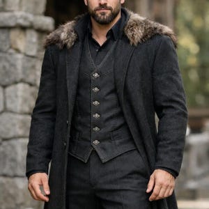 May include: A dark gray three-piece suit with a long coat and fur collar. The vest has decorative buttons. The man is wearing a black shirt. The suit is made of a heavy fabric, suitable for cold weather.