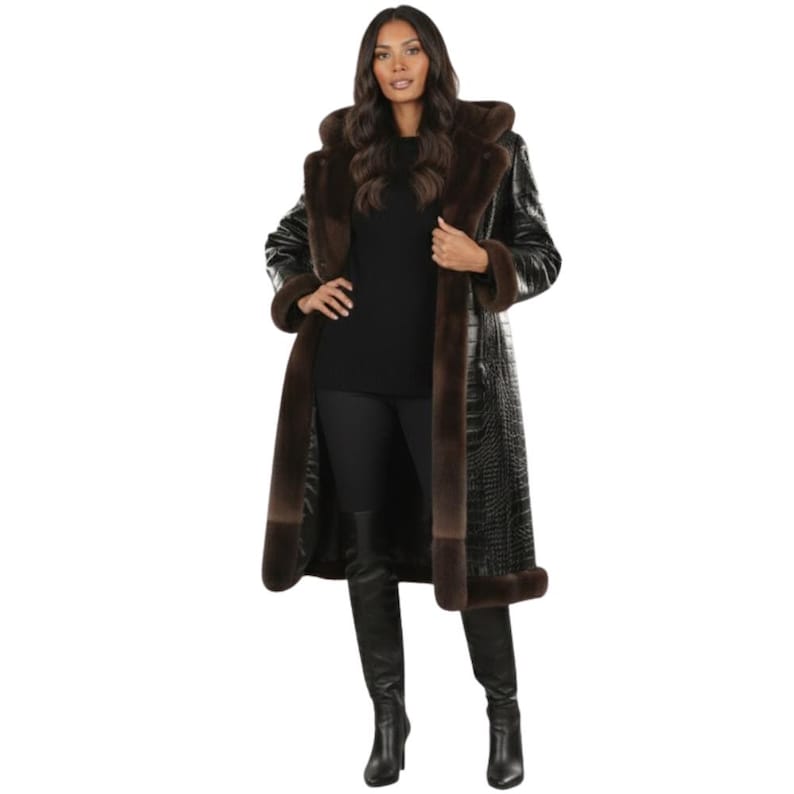 May include: A long black coat with brown fur trim and a hood. The coat has a crocodile skin texture and is worn over a black outfit. The fur trim is around the hood, cuffs, and down the front of the coat.
