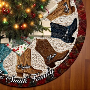 Puede incluir: Una falda para el árbol de Navidad con un diseño acolchado y botas de vaquero bordadas. Cada bota es de un color diferente y tiene un nombre. Las palabras "The Smith Family" están escritas en cursiva en la parte inferior.