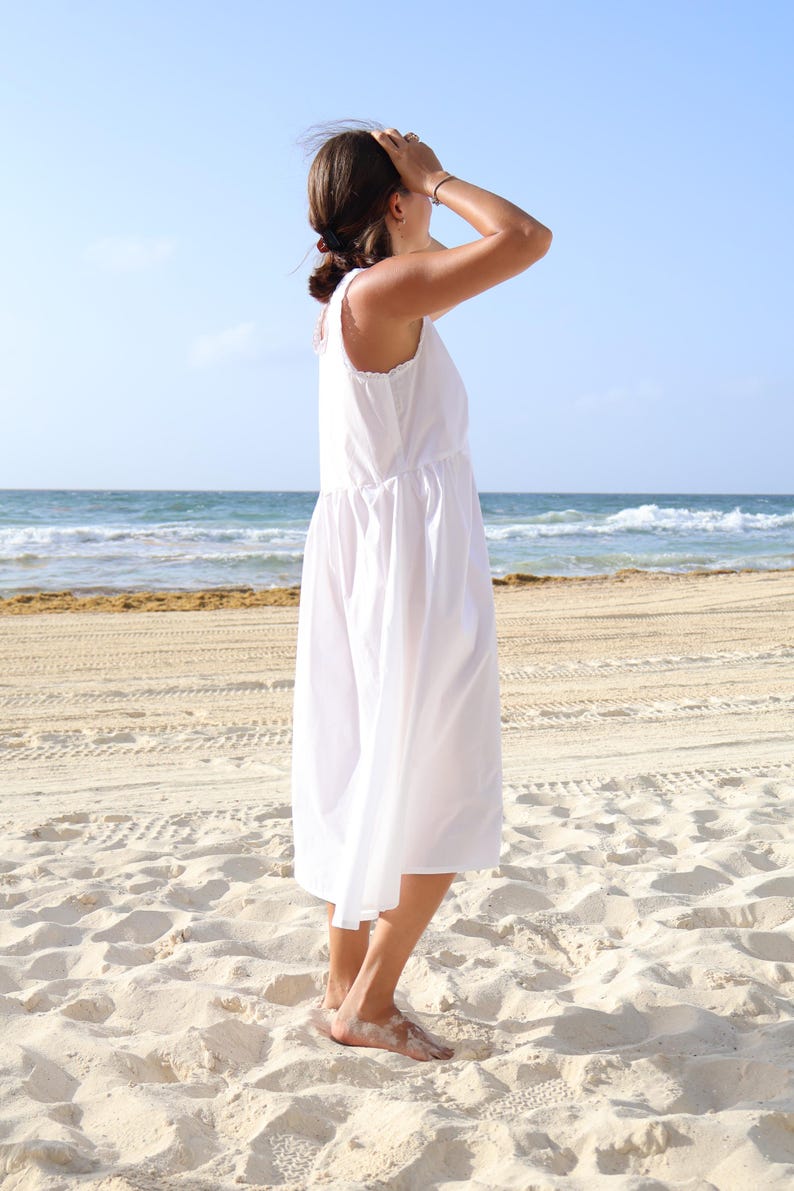 Peut inclure: Une robe midi blanche sans manches avec une encolure ronde, un corsage ajust&eacute; et une jupe ample et fluide qui tombe sous les genoux. Le v&ecirc;tement pr&eacute;sente un design simple et &eacute;pur&eacute;, mettant en valeur une couleur blanche unie sur tout le tissu.