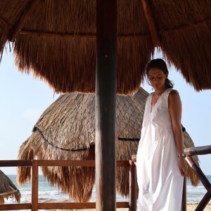 Peut inclure: Une robe midi blanche sans manches avec une encolure en V orn&eacute;e de d&eacute;tails en dentelle d&eacute;licate sur les bords. La robe pr&eacute;sente une silhouette d&eacute;contract&eacute;e et fluide qui tombe sous les genoux, confectionn&eacute;e dans un tissu blanc uni l&eacute;ger.