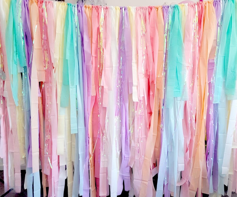Op de afbeelding: Een kleurrijke achtergrond met verticale stroken pastelkleurig stof in roze, perzik, geel, blauw en paars. Sommige stroken hebben een glinsterend, iriserend effect, wat een feestelijke uitstraling geeft. Ideaal voor feesten.