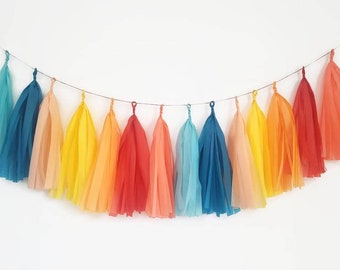 May include: A rainbow tissue paper tassel garland with alternating colors of teal, peach, yellow, orange, red, and pink.