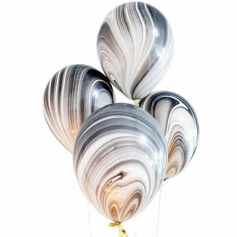 May include: Four black and white marble patterned balloons. The balloons are shiny and have a swirl pattern.