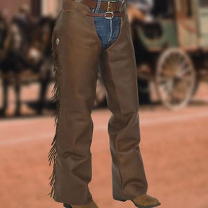 Peut inclure: Chaps en cuir marron avec des franges sur les côtés. Les chaps sont portés sur un jean bleu et une ceinture en cuir marron avec une boucle argentée. Ils sont associés à des bottes de cowboy marron, pour un look western classique.