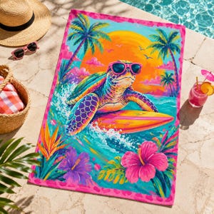 May include: Beach towel with a colorful illustration of a surfing turtle wearing sunglasses, set against a tropical sunset scene with palm trees and hibiscus flowers. The towel has a pink border and is placed near a pool.