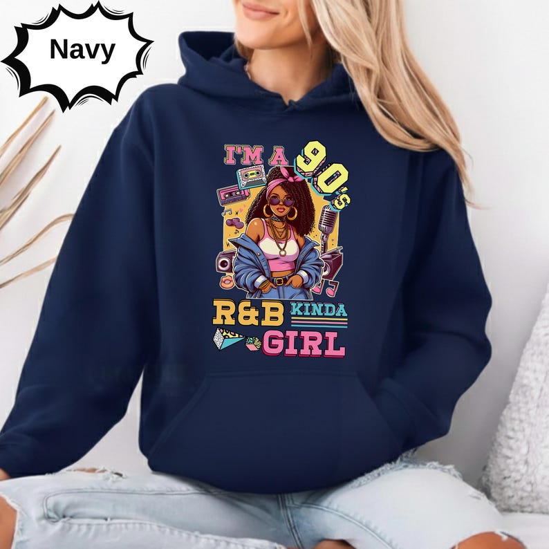May include: Navy blue hoodie with a graphic featuring a 90s R&B theme. The design includes a cartoon woman, a microphone, and the text "I'M A 90'S R&B KINDA GIRL". The hoodie has a front pocket and a drawstring hood.