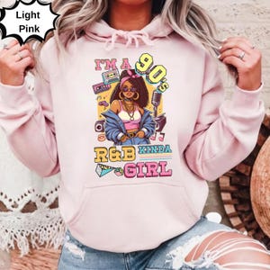May include: Light pink hoodie with a graphic of a woman in 90s style, with the text "I'm a 90's R&B Kinda Girl". The graphic includes a boombox, cassette tapes, and a microphone.