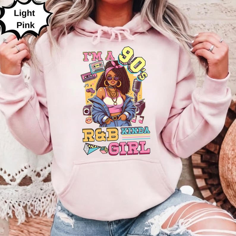 May include: Light pink hoodie with a graphic of a woman in 90s style, with the text "I'm a 90's R&B Kinda Girl". The graphic includes a boombox, cassette tapes, and a microphone.