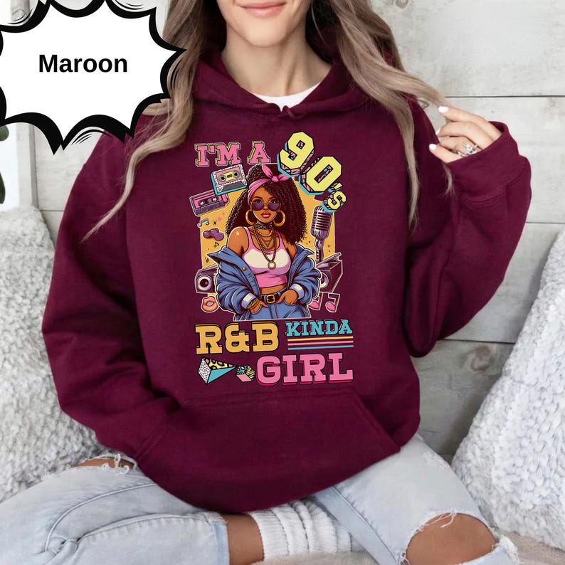May include: Maroon hoodie with a graphic that reads "I'm a 90's R&B Kinda Girl." The graphic features a cartoon woman wearing sunglasses, a denim jacket, and a pink top. The design includes a cassette tape, microphone, and musical notes.