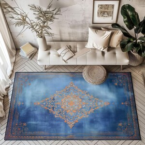 May include: A blue area rug with an ornate orange central medallion and border. The rug has a distressed, vintage look, with a gradient of blue hues. The rug is rectangular and placed on a wooden floor.