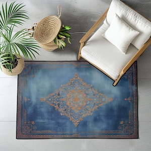 May include: Overhead view of a blue and orange patterned rug. The rug has a central diamond-shaped design and a border with intricate details. A white chair with a pillow is on the right. A potted plant and a woven basket are on the left.