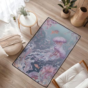 Peut inclure: Tapis rectangulaire avec un motif de m&eacute;duse dans des tons de violet, rose et bleu. Le tapis a une bordure noire et repr&eacute;sente une sc&egrave;ne sous-marine avec des poissons et du corail. Il est pos&eacute; sur un sol en bois.