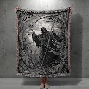 Könnte beinhalten: Schwarz-weiße gewebte Decke mit einer detaillierten Illustration des Sensenmanns, der einen Schädel und eine Sense in einem dunklen Wald hält. Die Decke hat einen Fransenrand und ein gotisches Thema.