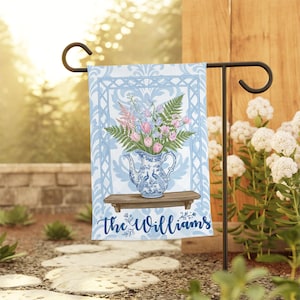 May include: A rectangular garden flag featuring a light blue and white damask pattern. The center displays a blue and white porcelain pitcher filled with pink and blue flowers and green ferns on a wooden shelf. The text "the Williams" is below.