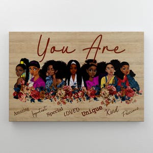 May include: Wooden wall art featuring a group of diverse women with floral accents. The words "You Are" are written in a cursive font above the women. Below the women are the words "Amazing, Important, Special, Loved, Unique, Kind, Precious."