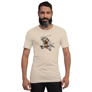 May include: A beige t-shirt with a cartoon illustration of a horned lizard wearing a scarf and glasses. The lizard is saying "I'm a what?"