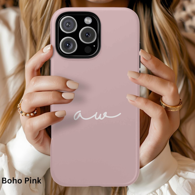 K&ouml;nnte beinhalten: Eine Boho Pink Handyh&uuml;lle mit wei&szlig;em "aw"-Schriftzug. Die H&uuml;lle hat eine einfarbige, ged&auml;mpfte rosa Farbe und einen Kameraausschnitt. Die Handyh&uuml;lle wird von einer Person gehalten.