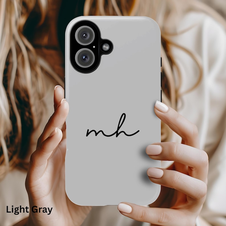 K&ouml;nnte beinhalten: Hellgraue Handyh&uuml;lle mit den Initialen "mh" in schwarzer Schrift. Die H&uuml;lle hat einen Ausschnitt f&uuml;r eine Dual-Kamera und die Worte "Light Gray" stehen unten.