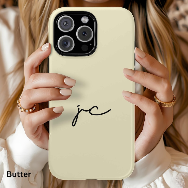 K&ouml;nnte beinhalten: Eine butterfarbene Handyh&uuml;lle mit einem schwarzen Kameramodul und den handgeschriebenen Initialen "jc". Das Wort "Butter" ist unten links aufgedruckt. Die H&uuml;lle ist f&uuml;r ein Smartphone konzipiert.