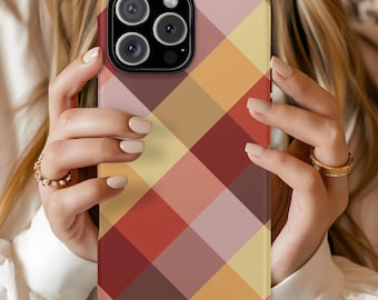 May include: A phone case with a colorful plaid pattern in shades of red, yellow, and brown. The case is held by a person, showcasing the phone's camera and design. The case has a smooth, glossy finish.