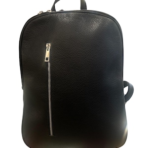 Puede incluir: Una mochila de cuero negro con una superficie texturizada. La mochila tiene una cremallera plateada y un asa pequeña en la parte superior. También hay un asa pequeña en el lateral.