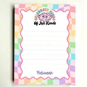 May include: A rectangular notepad with a pastel checkered border in shades of pink, yellow, green, and blue. The center features a pink brain illustration wearing purple glasses, the text Celebrate Minds Of All Kinds, and the name Marianne at the bottom.