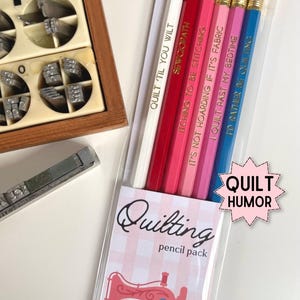May include: A set of six pencils in a clear plastic sleeve, each featuring a different color and a unique quilting-themed phrase in gold lettering. The packaging includes a pink and white checkered label with a sewing machine illustration and the text Quilting pencil pack and Quilt Humor.