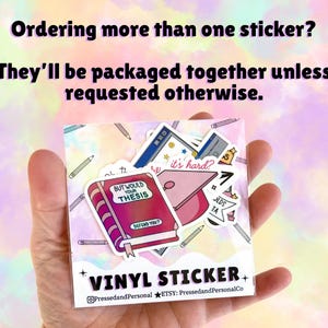 May include: A clear packet of vinyl stickers featuring academic-themed designs. The stickers include a book with the text "BUT WOULD YOUR THESIS DEFEND YOU?", a graduation cap, and other school-related graphics. The text "VINYL STICKER" is also visible.
