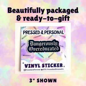 May include: A square vinyl sticker with the text "Dangerously Overeducated" in a decorative font. The sticker is surrounded by pencil illustrations and the words "PRESSED & PERSONAL" and "VINYL STICKER". The sticker is 3 inches in size.