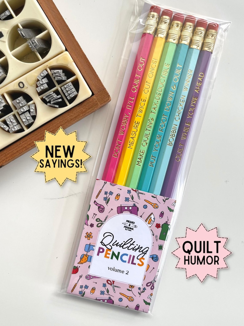 May include: A set of five hexagonal pencils in pink, yellow, green, light blue, and purple, each with a gold metal ferrule and eraser. The pencils feature gold foil text: DON'T WORRY, IT'LL QUILT OUT, MEASURE TWICE, CUT ONCE, MAKE QUILTING TAX-DEDUCTIBLE, PUT YOUR FOOT DOWN & QUILT, BOBBIN CHICKEN WINNER, and QUILT WHILE YOU'RE AHEAD.