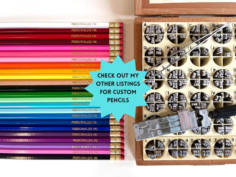 May include: A collection of multi-colored pencils arranged in a row, each featuring the text PERSONALIZE ME, alongside a wooden organizer box filled with metal letter stamps, a pair of metal tweezers, and a metal stamping tool for customization.
