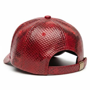 Peut inclure: Casquette de baseball rouge avec un motif peau de serpent. La casquette a une visi&egrave;re incurv&eacute;e, un bouton sur le dessus et une sangle r&eacute;glable avec une boucle dor&eacute;e. Fabriqu&eacute;e dans un mat&eacute;riau textur&eacute;.