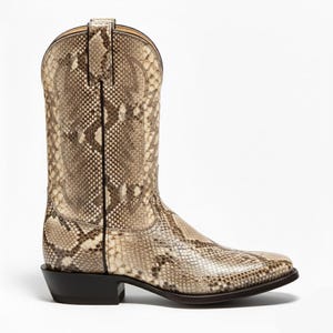 May include: A single cowboy boot with a snakeskin pattern in shades of tan, brown, and cream. The boot has a pointed toe, a stacked heel, and a tall shaft with decorative stitching. The boot is set against a white background.