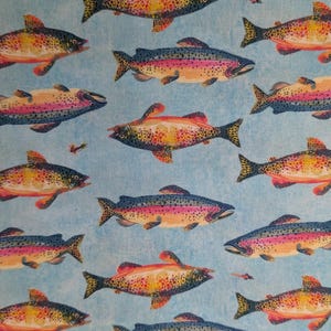 May include: A light blue fabric featuring a repeating pattern of rainbow trout. Each fish is depicted with a speckled body, a pinkish lateral stripe, and dark fins. Small, colorful fishing flies are interspersed between the trout illustrations.