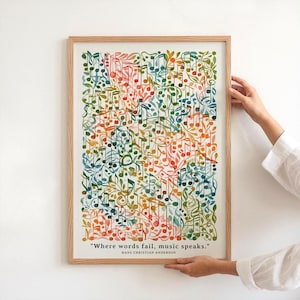Op de afbeelding: Een ingelijste kunstdruk met een kleurrijk aquarelontwerp van muzieknoten en bladeren. Het kunstwerk bevat de quote "Waar woorden falen, spreekt muziek." van Hans Christian Anderson. De lijst is gemaakt van lichtgekleurd hout.