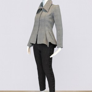 May include: A mannequin displays a stylish ensemble. The outfit includes a gray and white plaid jacket with a peplum waist and a zipper closure, paired with black pants. The mannequin wears white boots. The outfit is a size small.