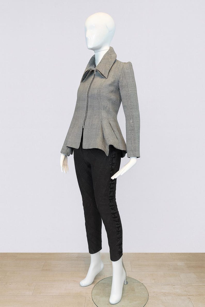 May include: A mannequin displays a stylish ensemble. The outfit includes a gray and white plaid jacket with a peplum waist and a zipper closure, paired with black pants. The mannequin wears white boots. The outfit is a size small.
