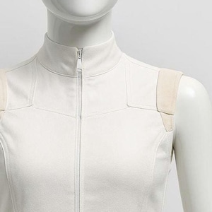 May include: A sleeveless off-white vest with a high collar and a central vertical zipper closure. The garment features structured shoulder panels in a lighter beige tone and is worn by a mannequin wearing iridescent pink and blue goggles.