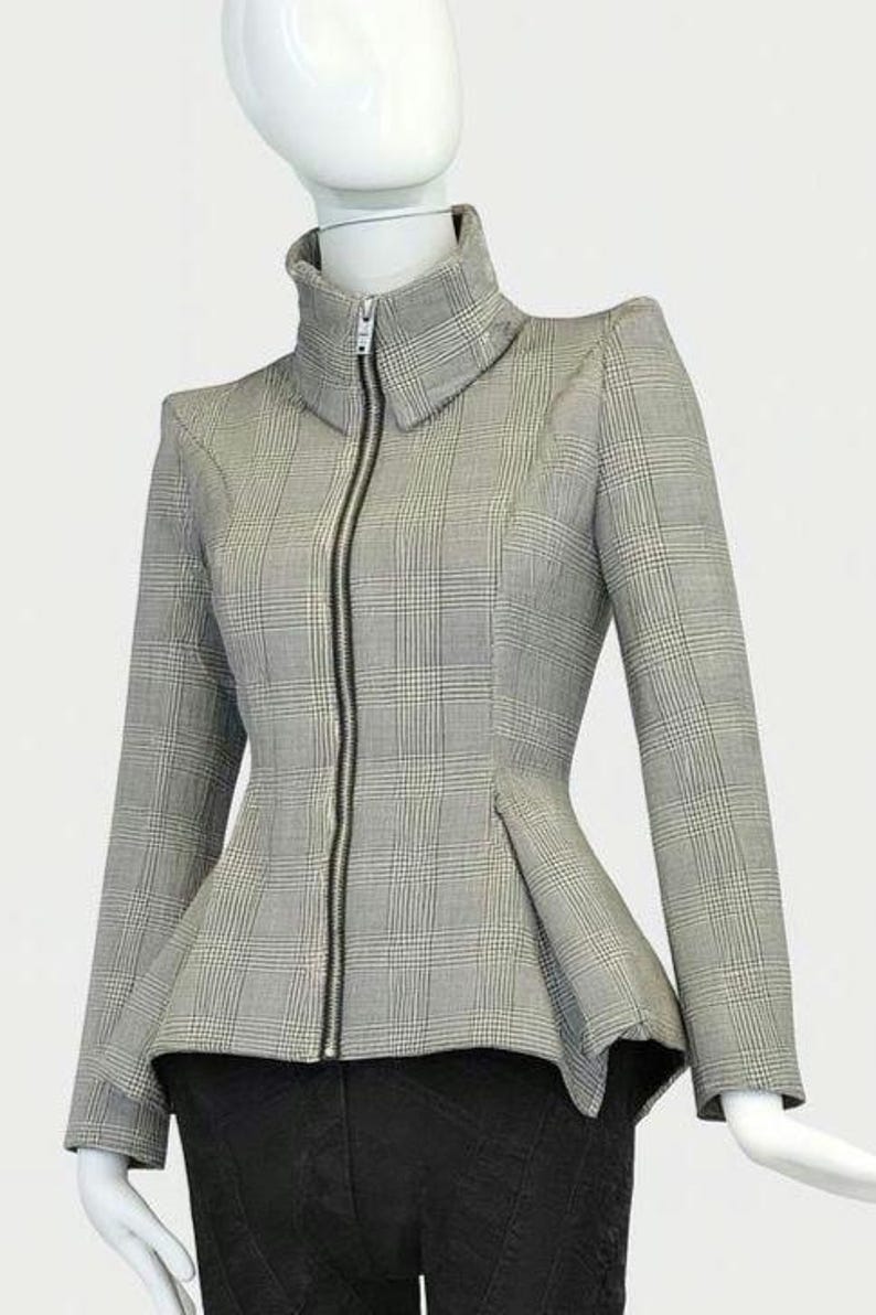 May include: A gray and white plaid jacket with a high collar and a black zipper. The jacket has long sleeves and a peplum waist. The jacket is displayed on a mannequin.