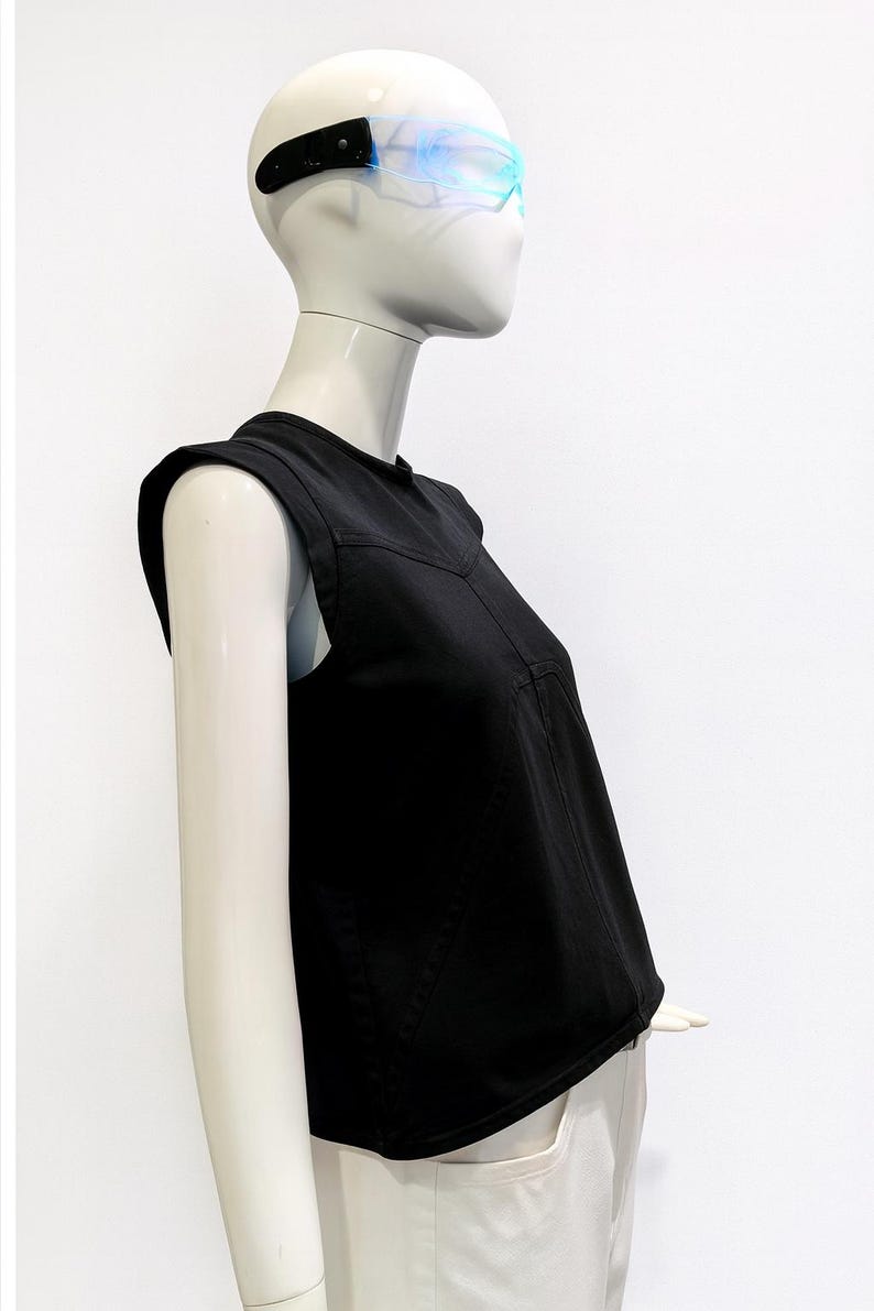May include: A black sleeveless top with structured shoulders and a V-shaped seam across the chest, worn by a mannequin sporting futuristic translucent blue-tinted visor glasses with black side frames against a plain white background.