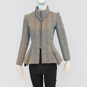 May include: A gray and white plaid jacket with a high collar and a peplum waist. The jacket has long sleeves and a black zipper down the front. The mannequin is also wearing black pants.