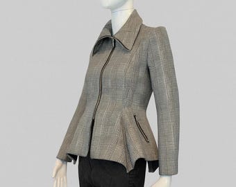 Könnte beinhalten: Eine grau-schwarz karierte Jacke mit hohem Kragen, durchgehendem Frontreißverschluss und ausgestelltem Schößchensaum. Die Jacke hat lange Ärmel und seitliche Taschen mit schwarzen Reißverschlüssen und wird über einer schwarzen Hose getragen.