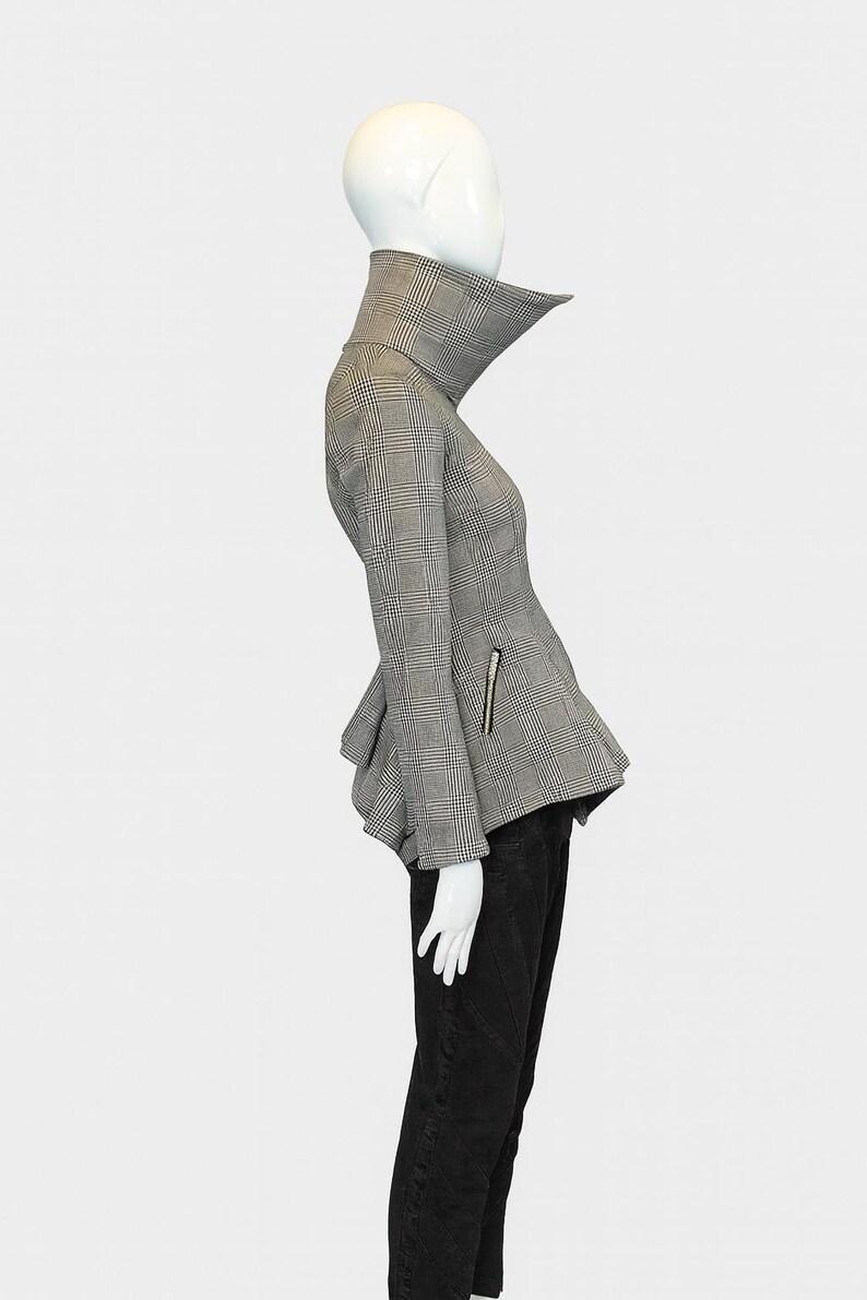 May include: A black and white plaid jacket with a high collar and peplum detail. The jacket has a zipper on the sleeve and is paired with black pants. The mannequin is on a white background.