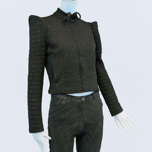 May include: A black long-sleeved jacket with a textured crocodile-skin pattern, a high collar, and a front zipper closure, paired with dark gray pants featuring prominent diagonal stitched seam detailing throughout the legs.
