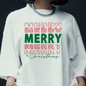 Puede incluir: Sudadera blanca de cuello redondo con las palabras "MERRY CHRISTMAS" en rojo, verde y estampado de leopardo. La palabra "MERRY" est&aacute; en letras verdes grandes. Una estrella est&aacute; al lado de la palabra "Christmas".